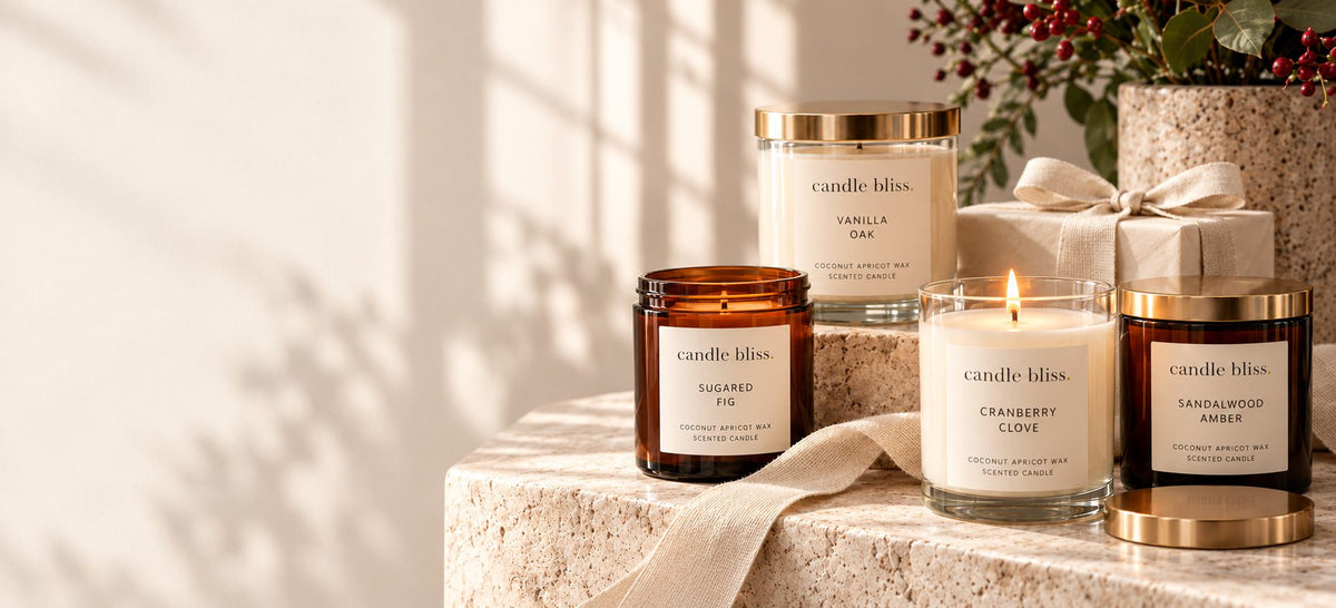 Candle Bliss candles in amber and clear jars on a stone pedestal with a gift box