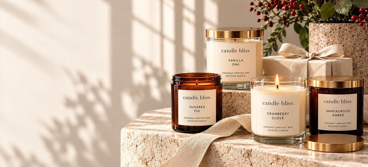 Sugared Fig, Vanilla Oak, Cranberry Clove and Sandalwood Amber candles on stone with berries and a gift box